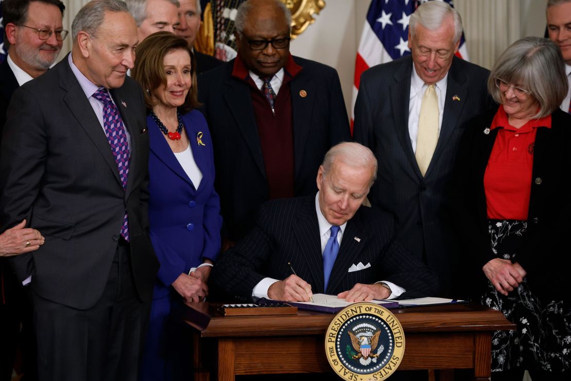 President Joe Biden signs the Postal Service Reform Act into law during an event with (L-R) Sen. Gary Peters (D-MI), Senate Majority Leader Charles Schumer (D-NY), Speaker of the House Nancy Pelosi (D-CA), House Majority Whip James Clyburn (D-SC), House Majority Leader Steny Hoyer (D-MD) and retired letter carrier Annette Taylor and others in the State Dining Room at the White House on April 6, 2022 in Washington, DC. (Photo by Chip Somodevilla/Getty Images)