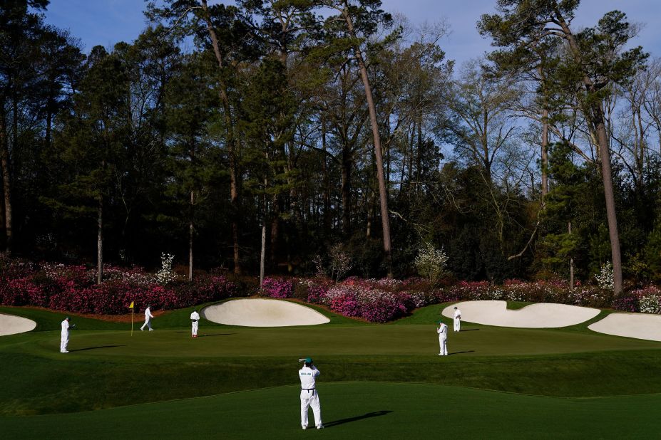 Caddies examine the 13th green during a practice round on Monday.