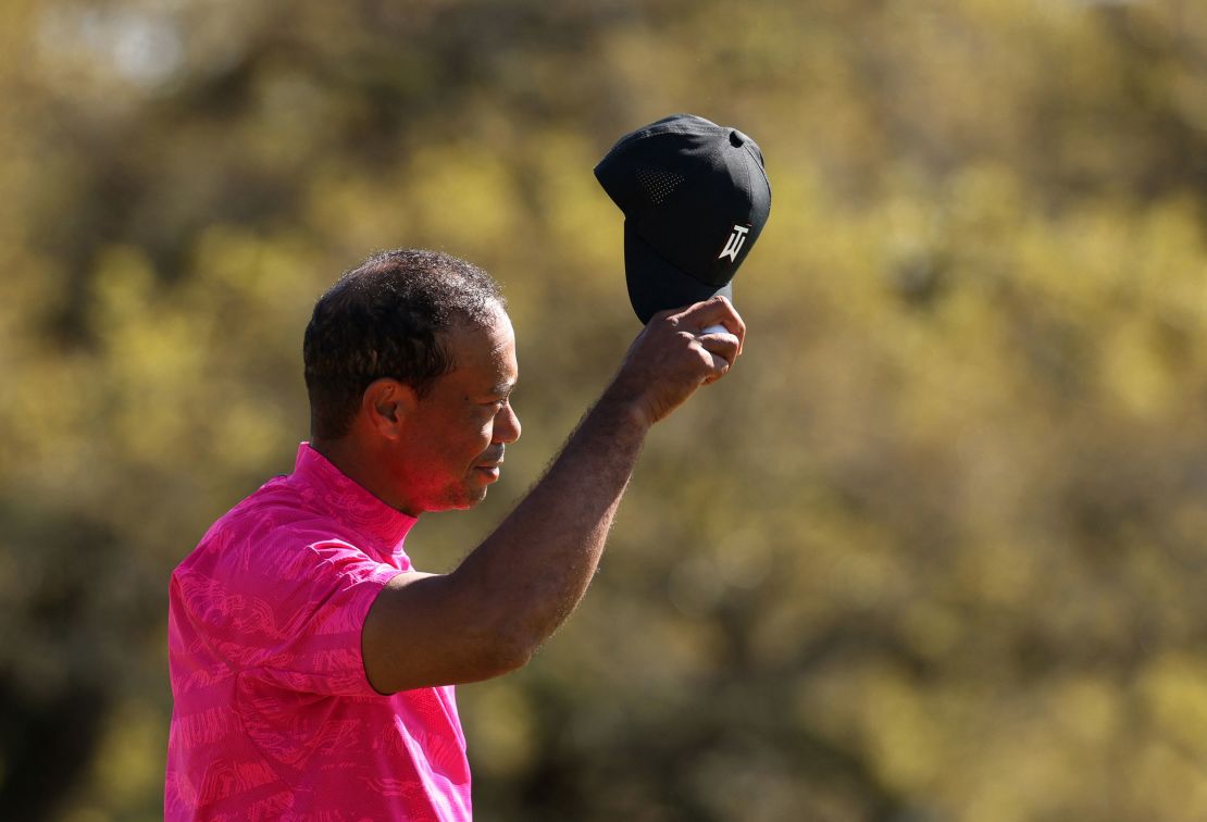 Woods salutes fans on the 18th green after he finishes the first round.