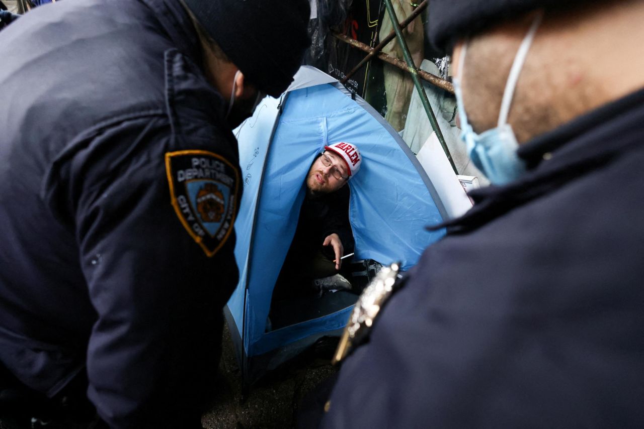 New York City police officers speak to a man living in a tent in Manhattan on Wednesday, April 6. New York City is <a href="https://www.cnn.com/2022/03/26/us/nyc-clears-homeless-encampments/index.html" target="_blank">clearing out encampments across the city</a> where homeless people are known to live. The plan, city officials said, is to place the people in shelters where they can access services for mental health, medical needs and housing.