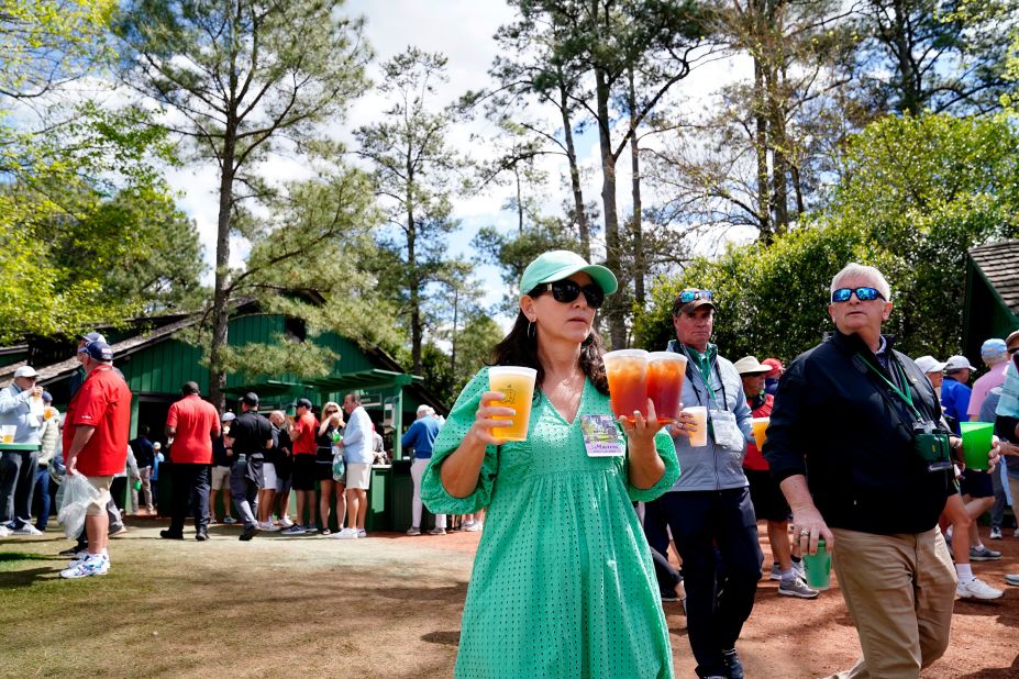 Fans carry beverages near the seventh hole leaderboard on Friday.