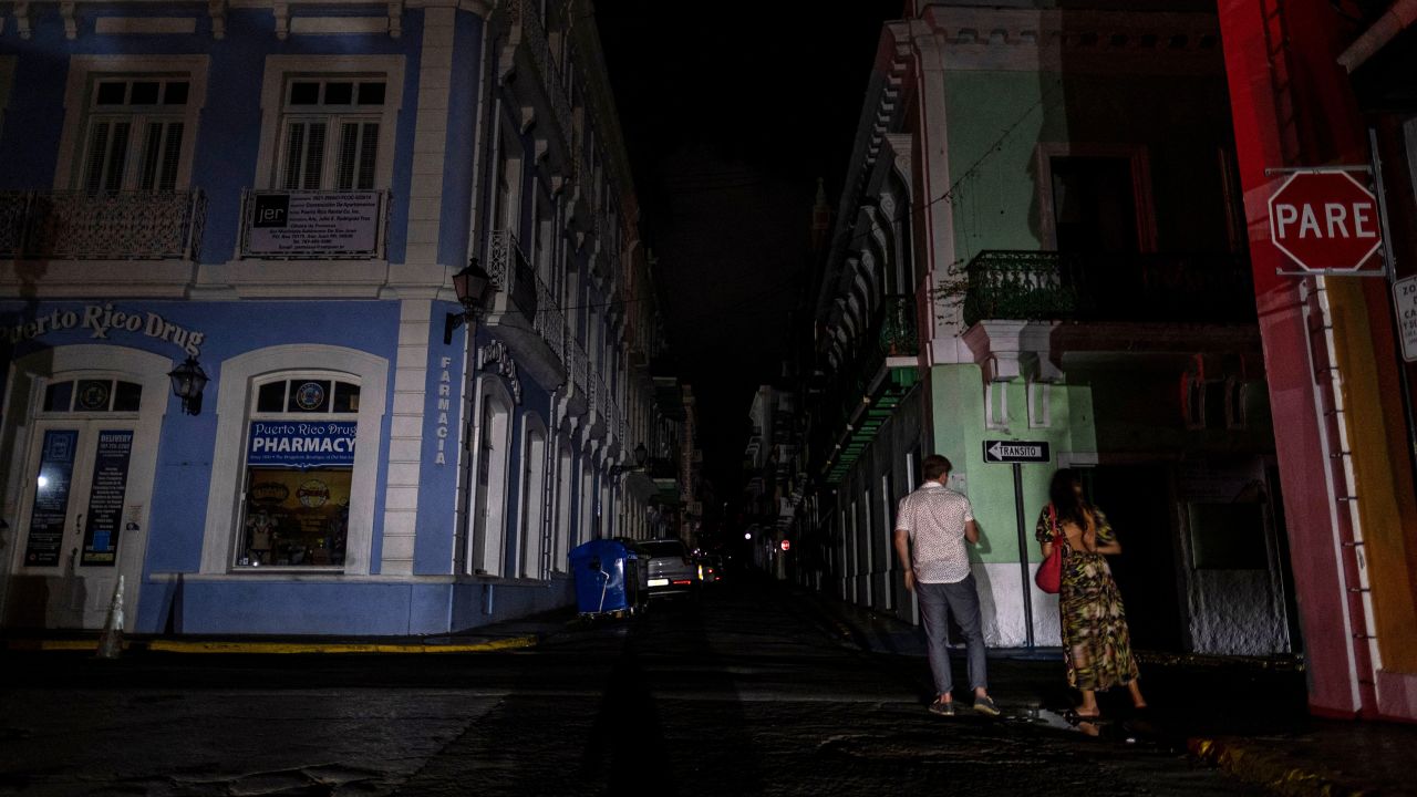 A couple walks on a dark street in San Juan after the April 6 blackout.