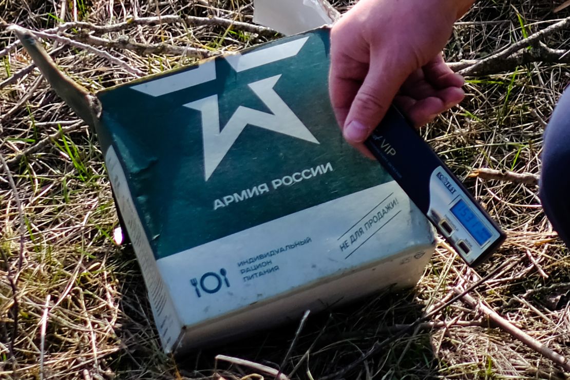 A Ukrainian soldier holds a radiation meter against a Russian military ration pack.