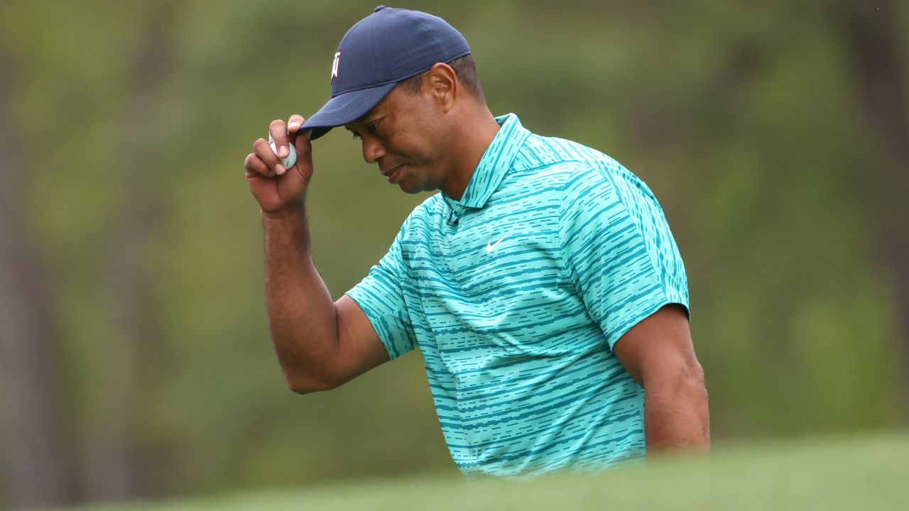 Woods tips his hat after making a bogey on the 12th green.