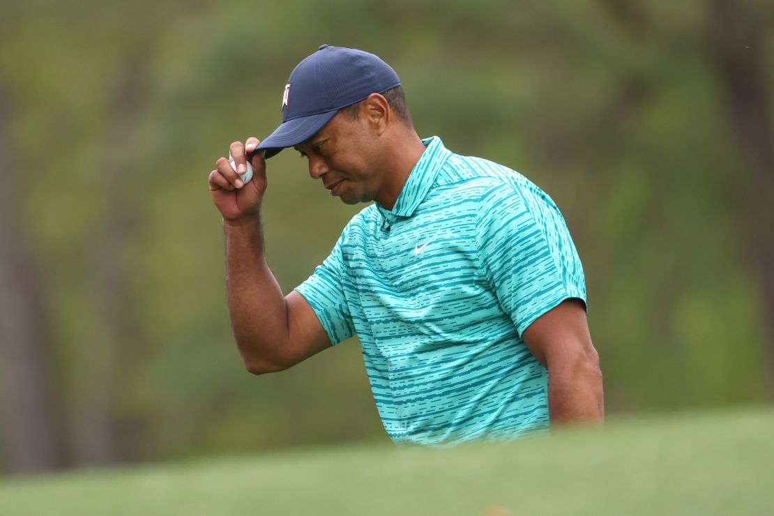 Woods tips his hat after making a bogey on the 12th green.