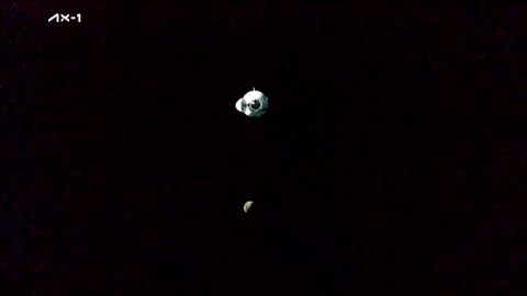 The SpaceX Ax-1 Dragon capsule approaches the International Space Station, with the moon in the background.