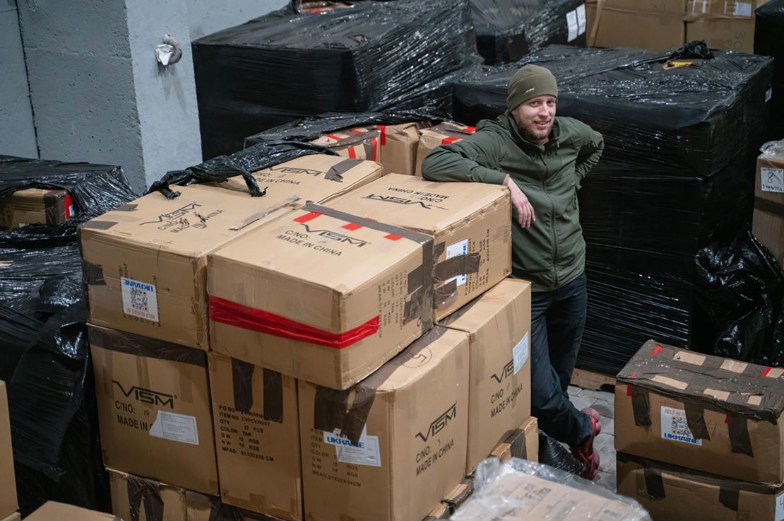 A Ukrainian civil defender standing with boxes of protective equipment provided by UACC after the shipment arrived in a Come Back Alive warehouse in Ukraine.