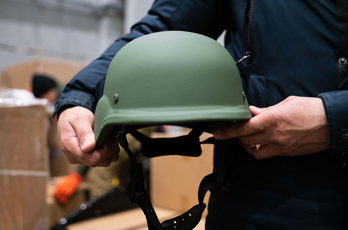 A protective helmet is held by a volunteer for the Come Back Alive foundation in one of its warehouses after a shipment of donations arrived in Ukraine.