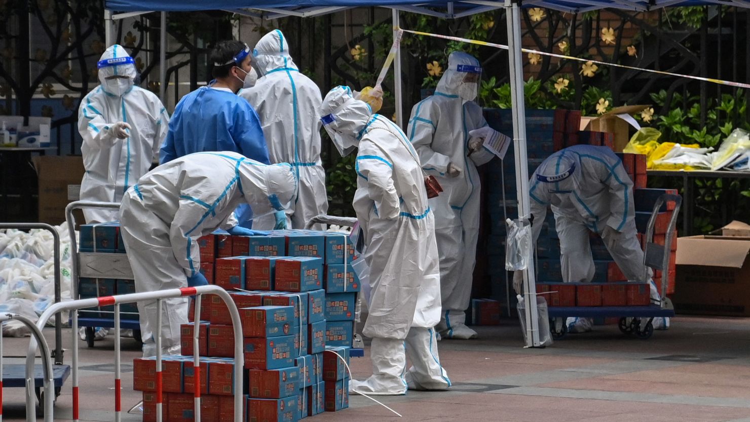 Workers wearing personal protective equipment are seen next to food delivered by the local government for residents in a compound during a Covid-19 lockdown in the Jing'an district in Shanghai on April 10, 2022.