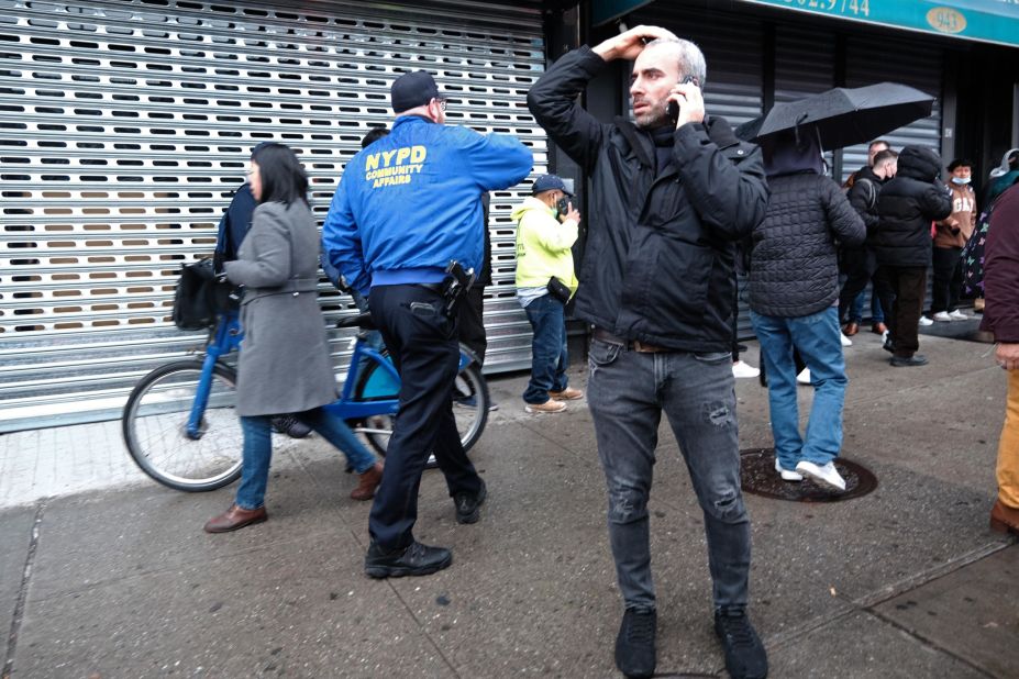 People stand near the entrance of the subway station after the shooting.