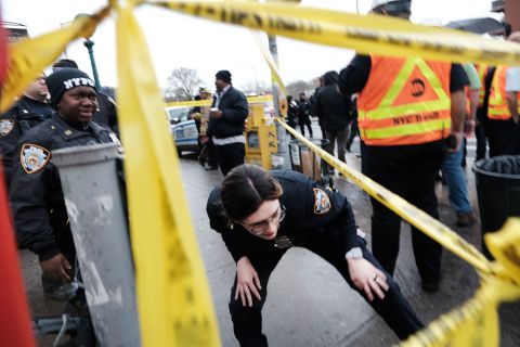 A police officer ducks under police tape at the scene.