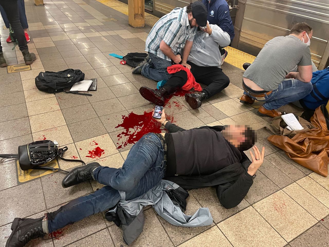 Injured people are seen on the platform of the 36th Street subway station on Tuesday. This photo was taken by photojournalist Derek French, who told CNN he leveraged his Red Cross first aid training to help victims. While helping them, French also discovered that he himself had been shot in the ankle and was bleeding. <strong><em>Editor's note:</em></strong><em> A blur has been applied here by CNN to protect the identity of the victim.</em>