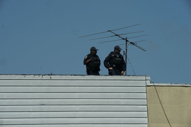 New York City police officers look down from a rooftop.
