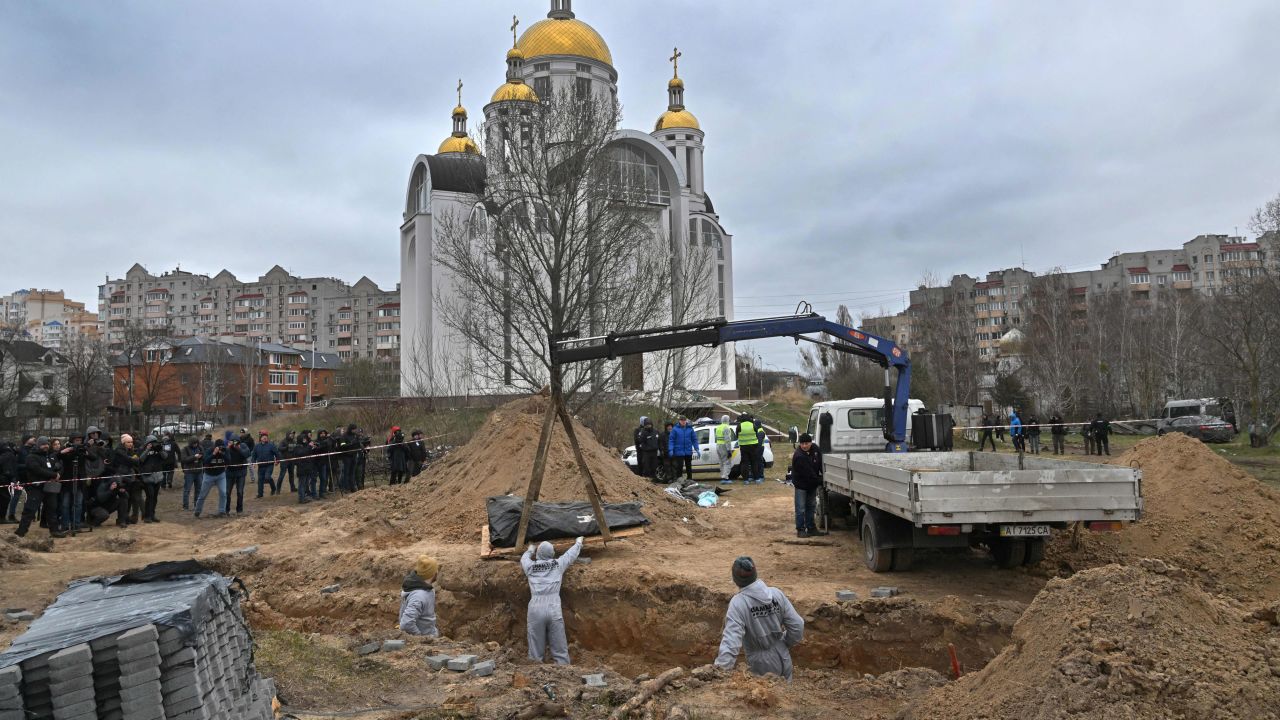 Journalists gather as bodies are exhumed from a mass grave in the grounds of St. Andrew and Pyervozvannoho All Saints church in Bucha, Ukraine, on April 13, 2022. 