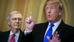 Senate Majority Leader Mitch McConnell, a Republican from Kentucky, left, listens while U.S. President Donald Trump speaks to members of the media while arriving to a Senate Republican policy luncheon at the U.S. Capitol in Washington, D.C., U.S., on Tuesday, March 26, 2019. 