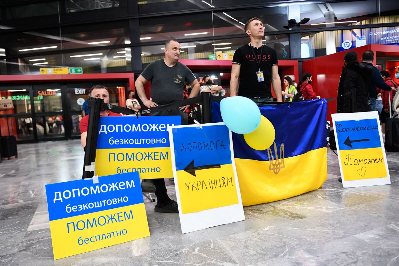 Volunteers with signs welcome Ukrainians as they arrive at the Tijuana airport on April 8. From there, volunteers shuttle them to shelters or hotels near the border.