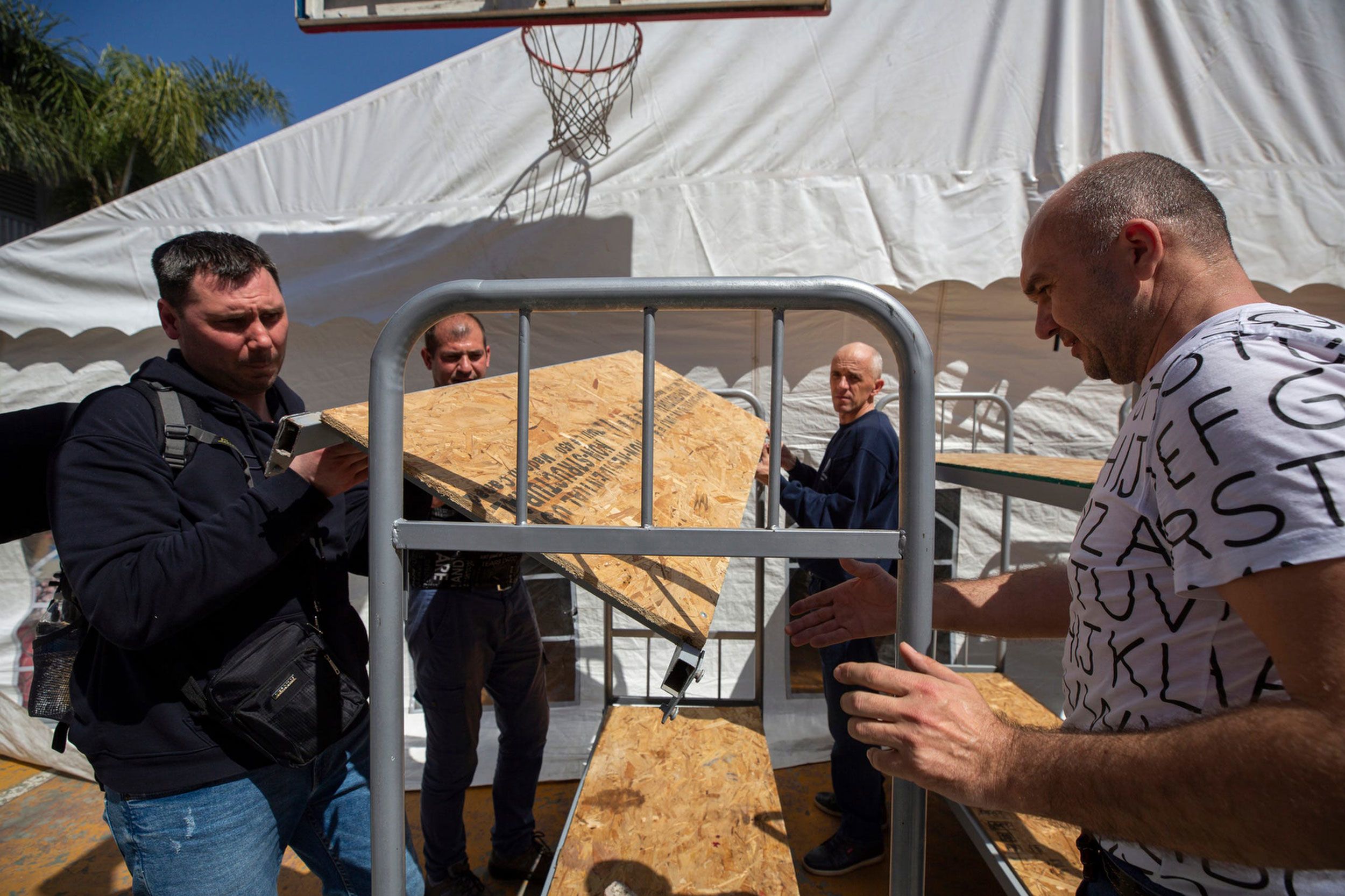 Ukrainians assemble bunk beds on April 6 for the Benito Juarez Sports Complex in Tijuana, where about 700 people are being housed.