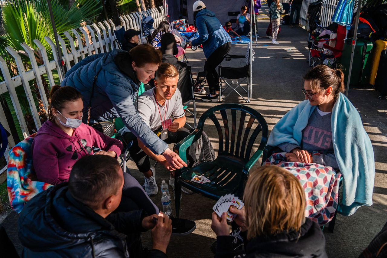 A volunteer and Ukrainians who fled to Mexico amid Russia's invasion of Ukraine play a card game while they wait at a makeshift camp near the San Ysidro Port of Entry of the US-Mexico border on April 4.