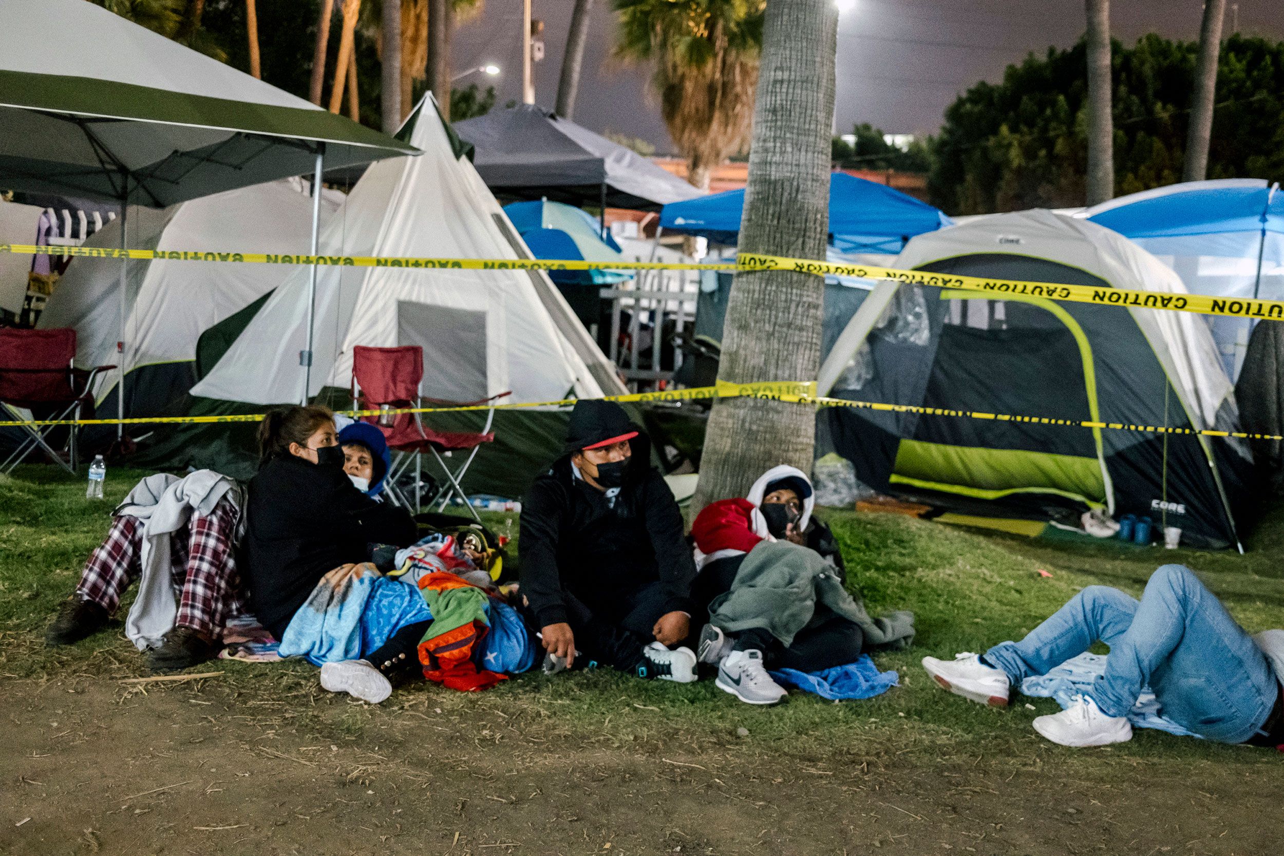 A group of Guatemalan migrants wait in front of a tent encampment housing Ukrainians on April 3.