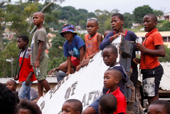 Children sit on part of the damaged church during Ramaphosa's visit.