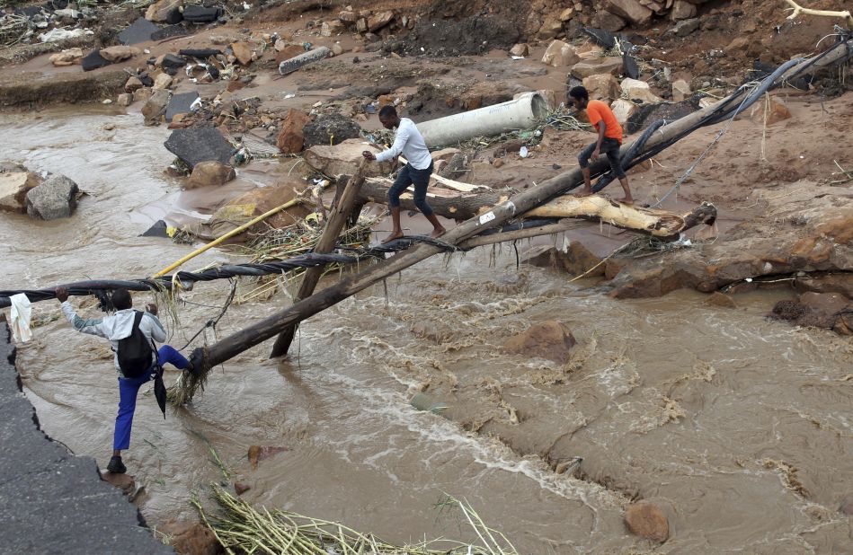 People walk across a makeshift bridge after a bridge was swept away in Ntuzuma on April 12.
