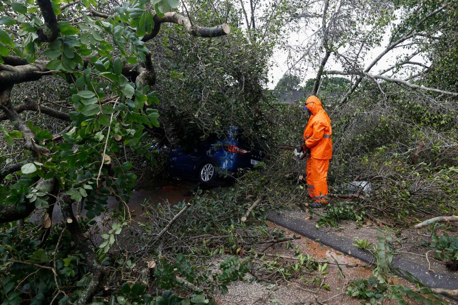 A municipal worker uses a chainsaw to cut branches off a tree that fell onto a car in Pinetown on April 12.