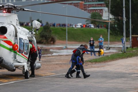 A rescue worker walks with a man who was helped from a flooded workplace near Umlazi on April 12.