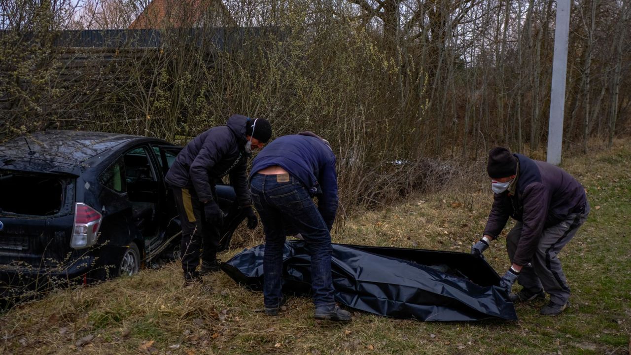 Volunteers collect the body of a man who was shot while driving his car in Borodianka, Ukraine.