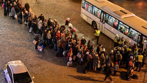 Refugees from Ukraine line up to get on buses to other destinations in Poland, outside the train station in Przemysl, near the Ukrainian-Polish border in southeastern Poland on March 16, 2022.