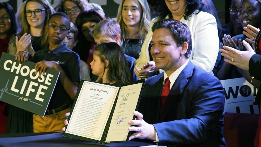Florida Gov. Ron DeSantis holds up a 15-week abortion ban law after signing it, Thursday, April 14, 2022, in Kissimmee, Fla. The move comes amid a growing conservative push to restrict abortion ahead of a U.S. Supreme Court decision that could limit access to the procedure nationwide.   (AP Photo/John Raoux)