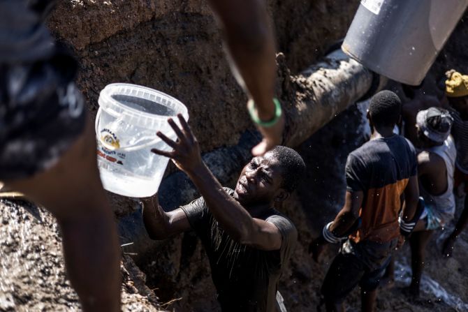 Residents collect clean water from a broken pipe on the side of a road in Amaoti on Thursday, April 14.