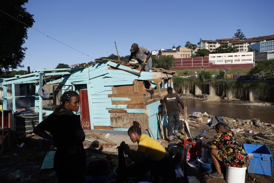 People wash their clothes as others work to rebuild a damaged home in Durban on April 14.