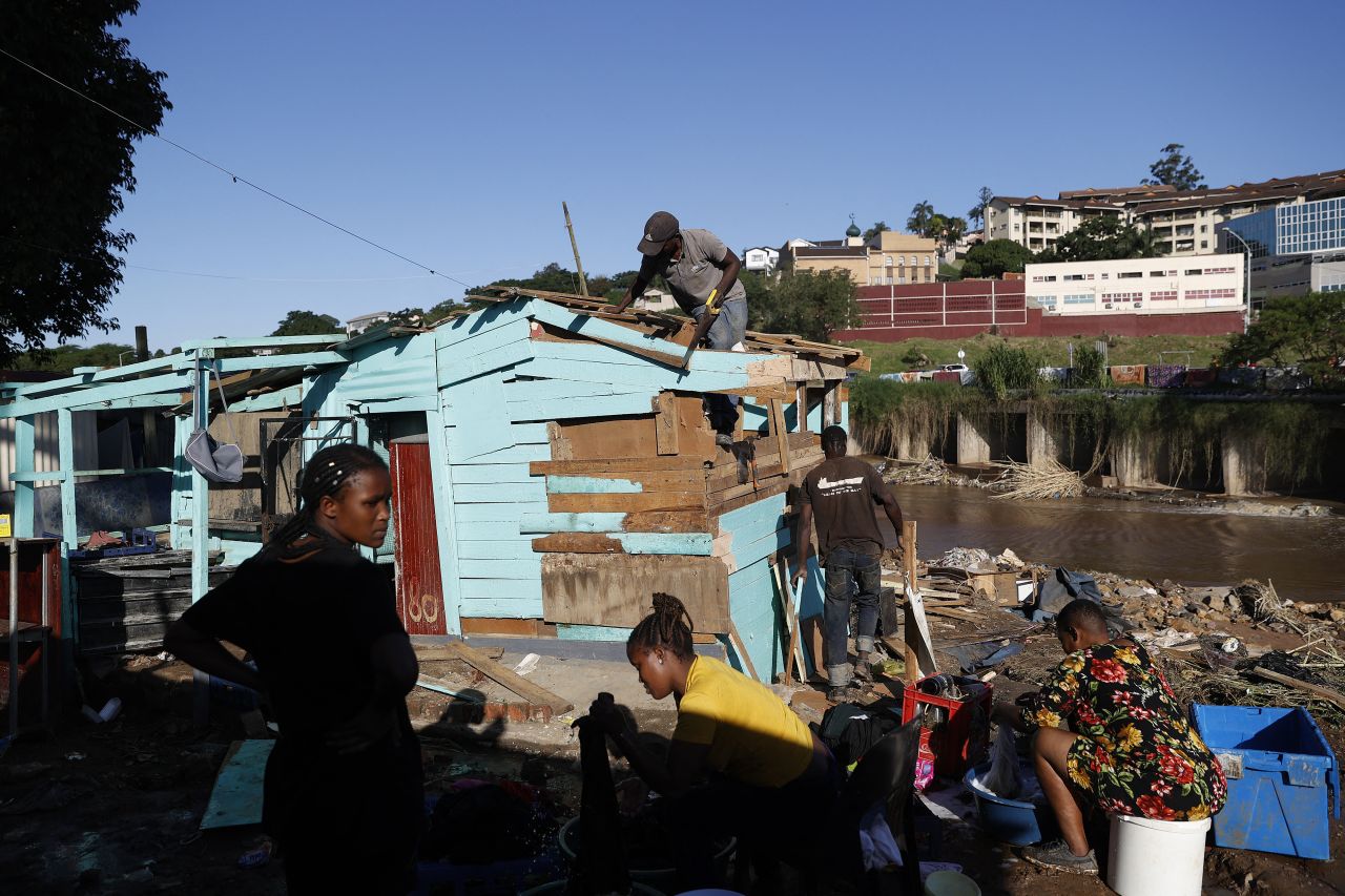 People wash their clothes as others work to rebuild a damaged home in Durban on April 14.
