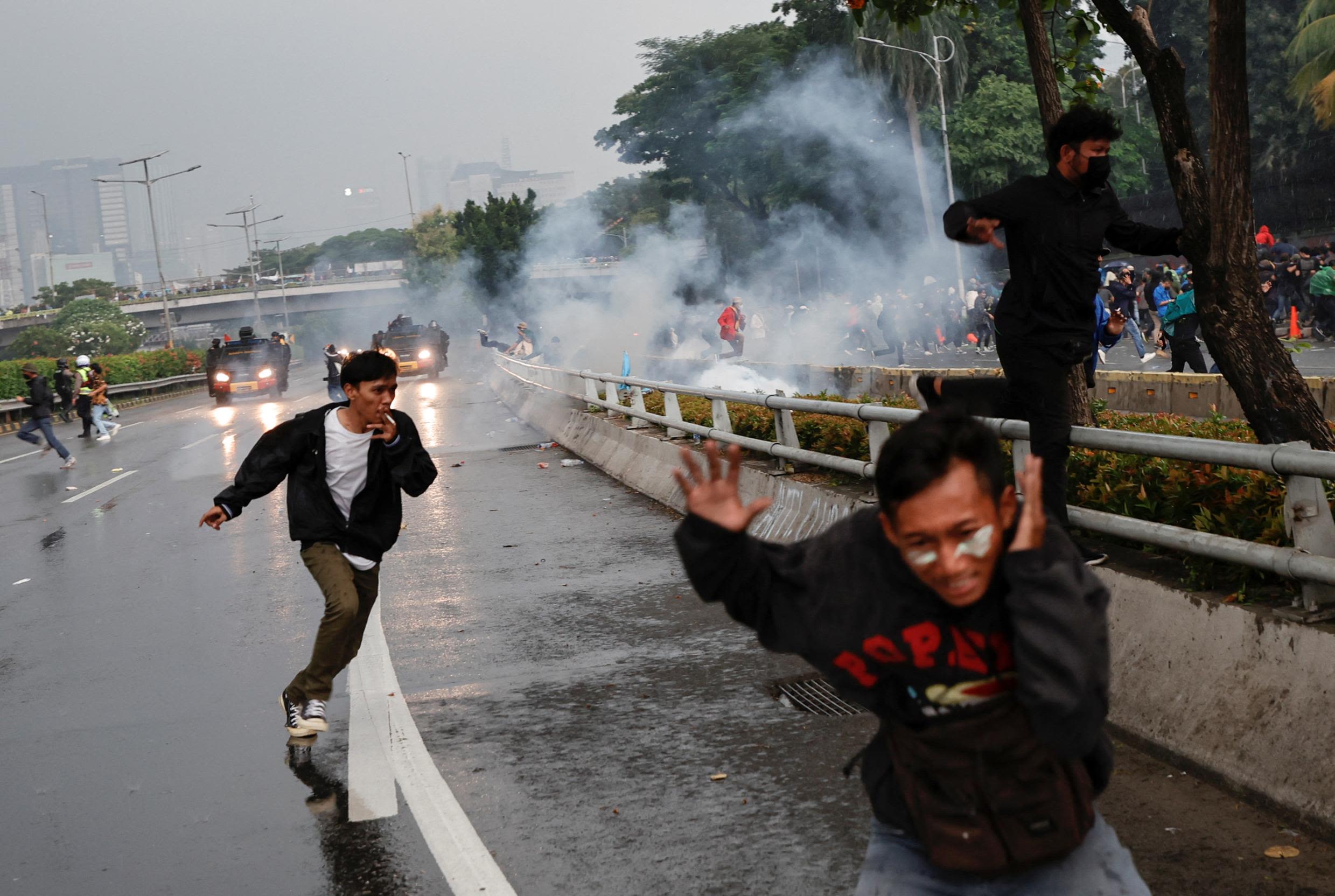 Protesters run away after police fired tear gas to disperse a rally outside Indonesia's parliament in Jakarta on Monday, April 11.