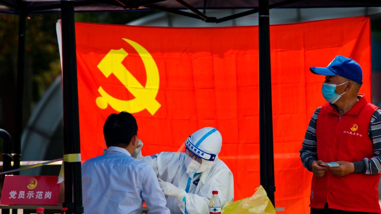 A medical worker tests a resident for Covid-19 in front of the flag of the Communist Party of China on April 12, 2022 in Jiangsu's province's Zhenjiang city.