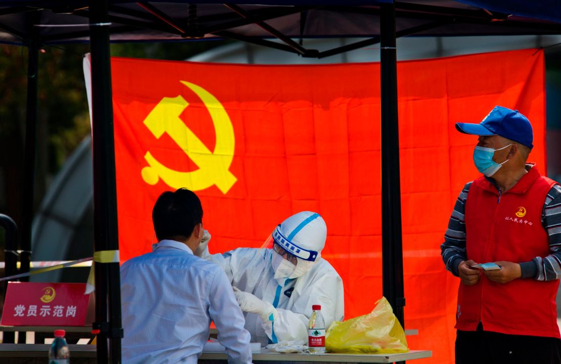 A medical worker tests a resident for Covid-19 in front of the flag of the Communist Party of China on April 12, 2022 in Jiangsu's province's Zhenjiang city.