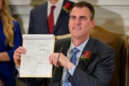 Oklahoma Gov. Kevin Stitt holds up the bill he signed on Tuesday, making it a felony to perform an abortion, punishable by up to 10 years in prison. 