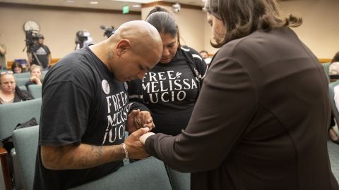 John Lucio, left, prays with his wife, Michelle Lucio, center, and Jennifer Allmon, executive director of the Texas Catholic Conference of Bishops, before a hearing about his mother by the Interim Study Committee on Criminal Justice Reform.