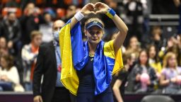 Ukraine's Dayana Yastremska, wrapped in the Ukrainian national flag, reacts at the end of the WTA 6eme Sens Open semi-final tennis match against Romania's Sorana Cirstea in Lyon, on March 5, 2022. Ukraine's Dayana Yastremska reached the Lyon WTA final on Saturday, just a week after escaping Russian bomb attacks on her home city of Odessa.