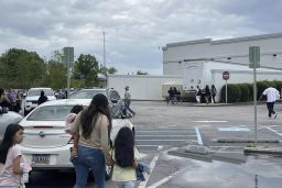 People walk through a parking lot at the Columbiana Centre mall in Columbia, S.C. on Saturday, April 16, 2022, as police investigate a shooting at the mall.