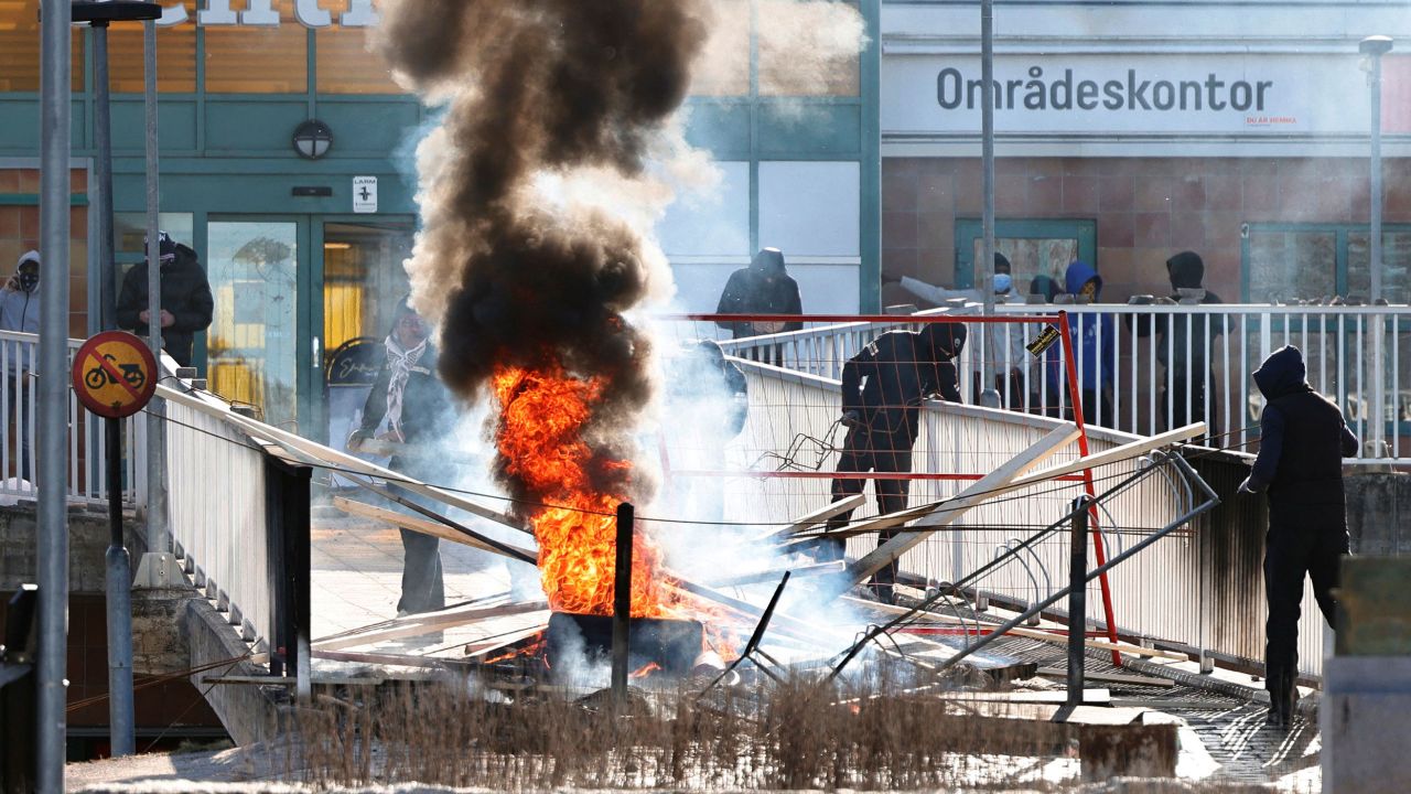 Protesters burn a barricade at the entrance to a shopping center during rioting in Norrköping, Sweden, on Sunday.