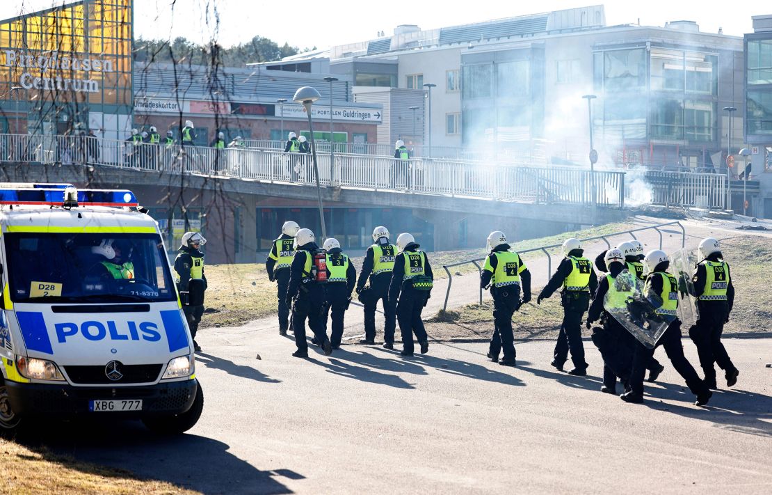 Riot police pass a barricade to enter a shopping center during rioting in Norrköping.