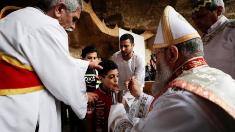 A boy receives communion from an Egyptian Coptic Orthodox Christian priest on April 17, during a Palm Sunday Mass in the Samaan el-Kharaz Monastery, in the Mokattam Mountain area of ​​Cairo, Egypt.