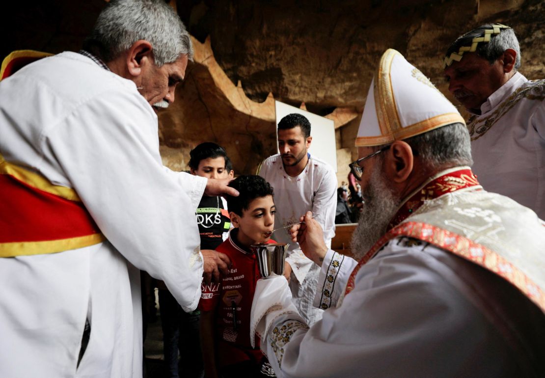A boy receives communion from an Egyptian Coptic Orthodox Christian priest on April 17, during a Palm Sunday Mass in the Samaan el-Kharaz Monastery, in the Mokattam Mountain area of Cairo, Egypt.