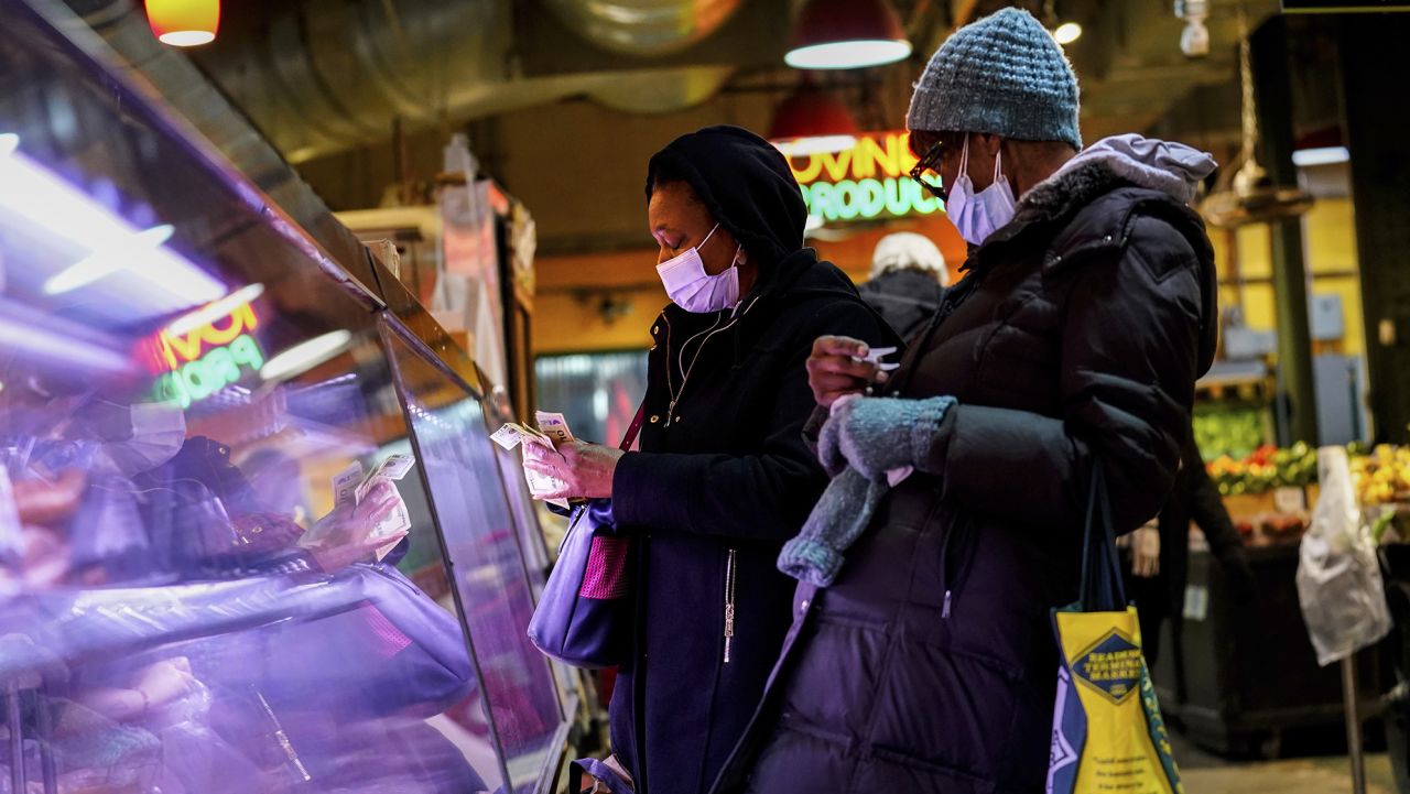 FILE - Customers wear face masks to protect against the spread of the coronavirus as they shop at the Reading Terminal Market in Philadelphia, Feb. 16, 2022. COVID cases are starting to rise again in the United States, with numbers up in most states and up steeply in several. One expert says he expects more of a "bump" than the monstrous surge of the first omicron wave, but another says it's unclear how high the curve will rise and it may be more like a hill. (AP Photo/Matt Rourke, File)