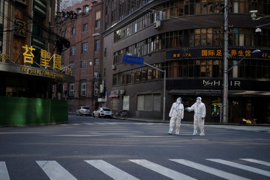 Workers in protective suits keep watch on a street during a lockdown in Shanghai, China.