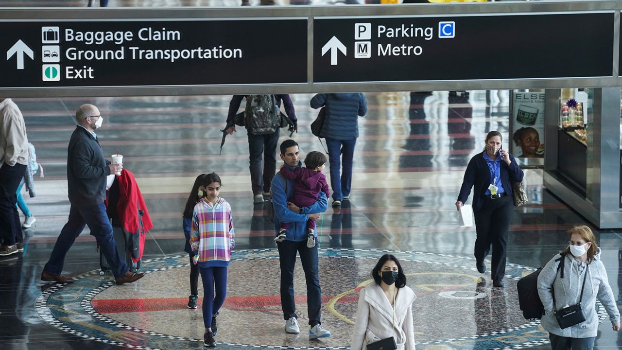A mix of masked and unmasked travelers make their way through Ronald Reagan Washington National Airport in Arlington, Virginia, on April 19, 2022. Navigating the latest mask changes will be challenging for travelers.