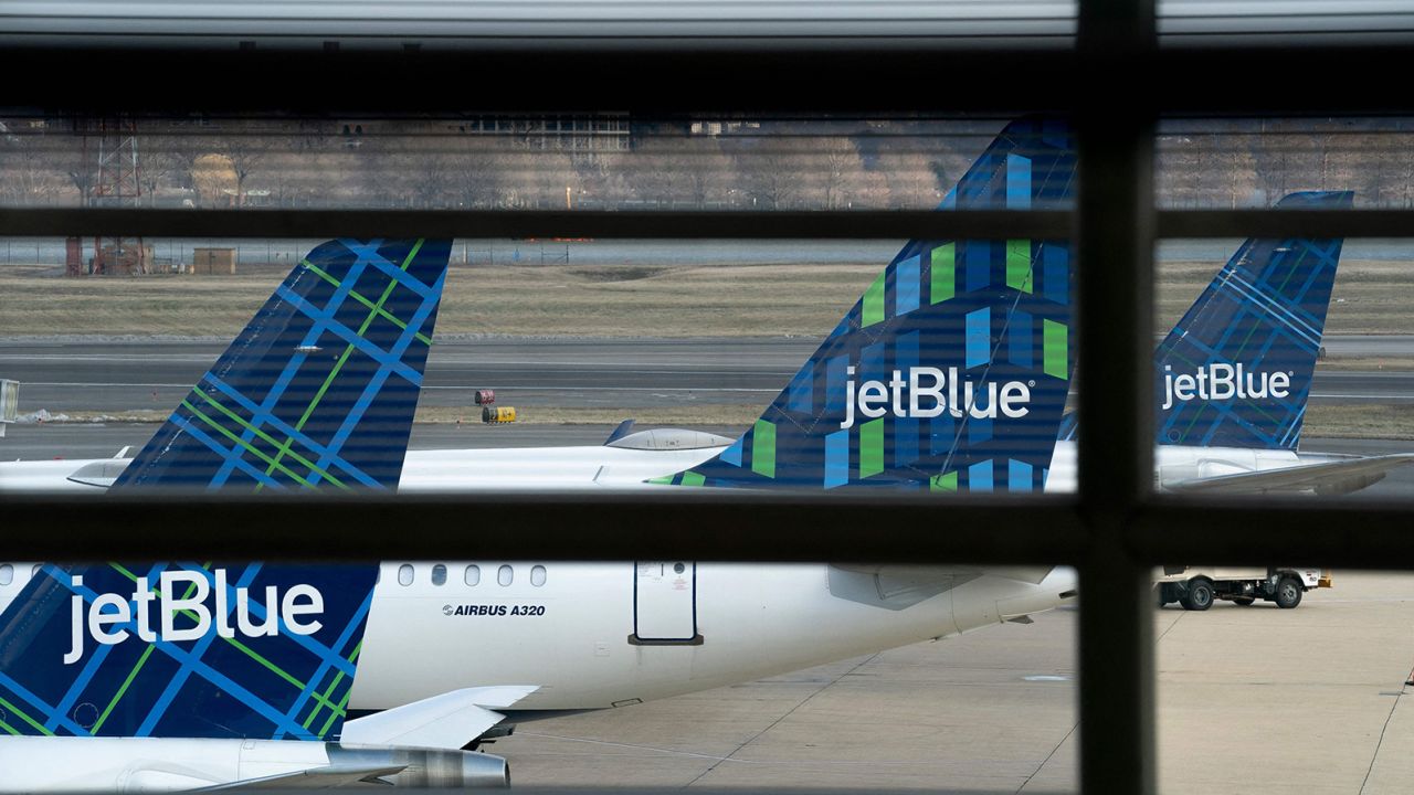 JetBlue planes sit at Ronald Reagan Washington National Airport in Arlington, Virginia, on January 18, 2022. JetBlue recently announced it's pulling back on its summer schedule.