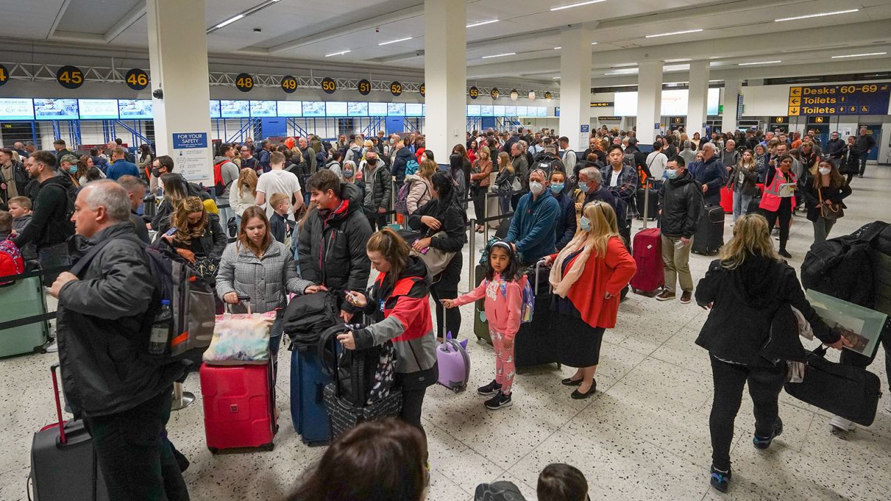 Passengers wait in line for check-in at Manchester Airport's Terminal 1 in England on April 16, 2022. Airports across the United Kingdom have struggled with getting flights off the ground because of staffing shortages.