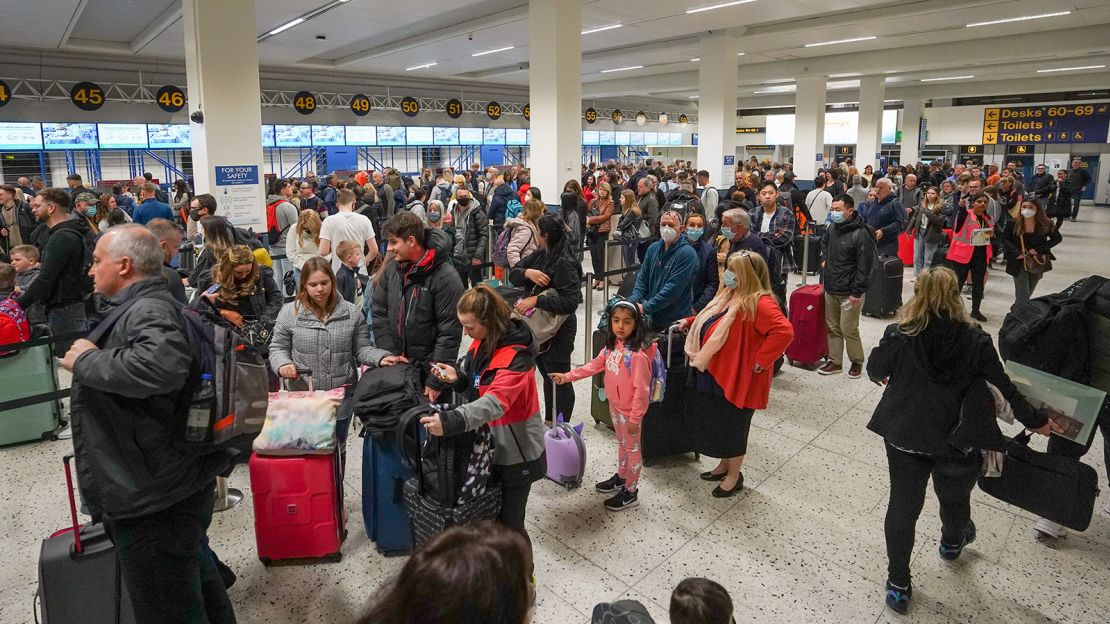 Passengers wait in line for check-in at Manchester Airport's Terminal 1 in England on April 16, 2022. Airports across the United Kingdom have struggled with getting flights off the ground because of staffing shortages.
